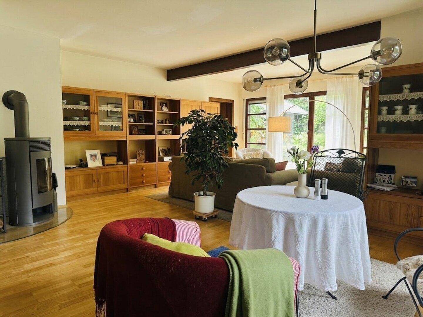 Helles Wohnzimmer mit modernem Holzofen, Holzeinbauschränken und Parkettboden.