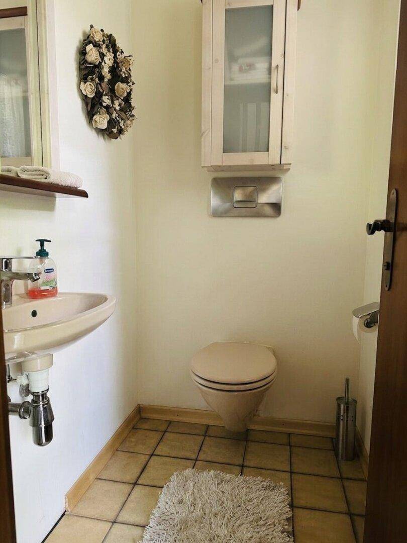 Kleines Gäste-WC mit Toilette, Einzelwaschbecken und hellen Fliesen.