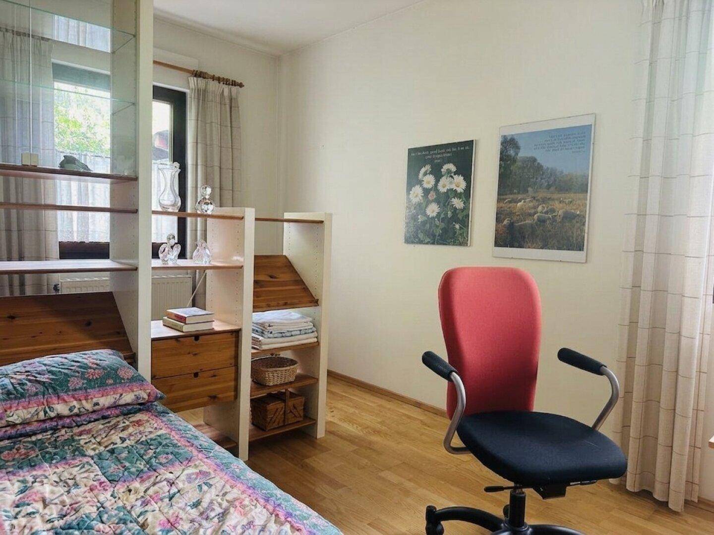 Helles Zimmer mit Einzelbett, Schreibtischbereich und Holzregalen, ideal als Gäste- oder Arbeitszimmer.