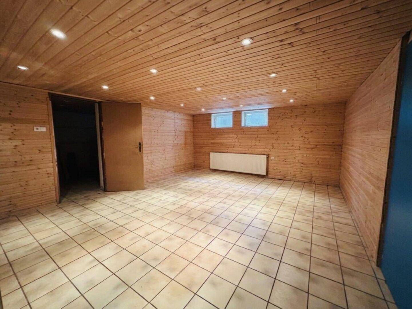 Ausgebauter Kellerraum mit Holzverkleidung an Wänden und Decke sowie Fliesenboden.