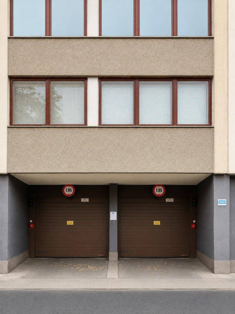 Fassade eines Gebäudes mit zwei braunen Garagentoren und Fenstern im Obergeschoss.