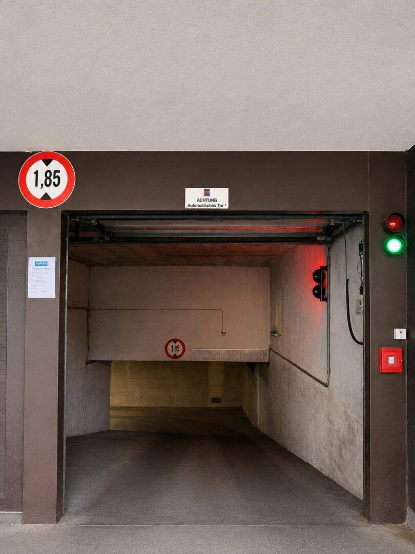 Einfahrt zu einer Tiefgarage mit Höhenbegrenzung und Ampelsystem.