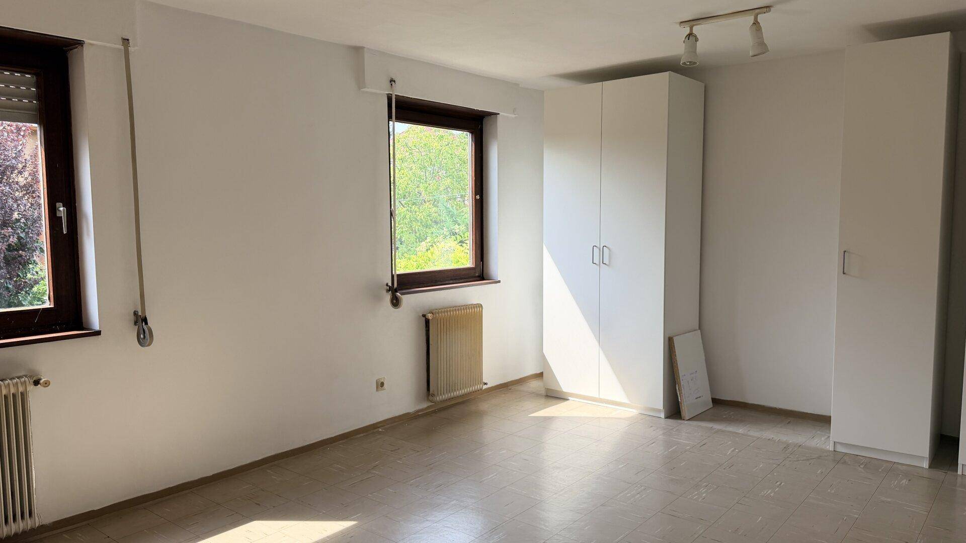 Schlafzimmer mit hellen Wänden, großem Fenster und praktischen Einbauschränken für Stauraum.