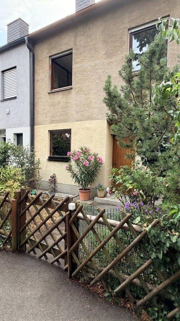 Vorderansicht des Hauses mit gepflegtem Vorgarten und traditionellem Holzzaun.