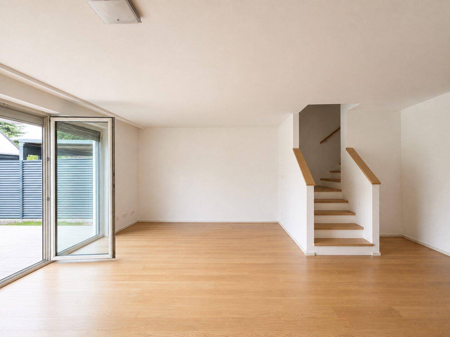 Geräumiger Wohnbereich mit Holzboden und Treppe, die in die oberen Stockwerke führt.