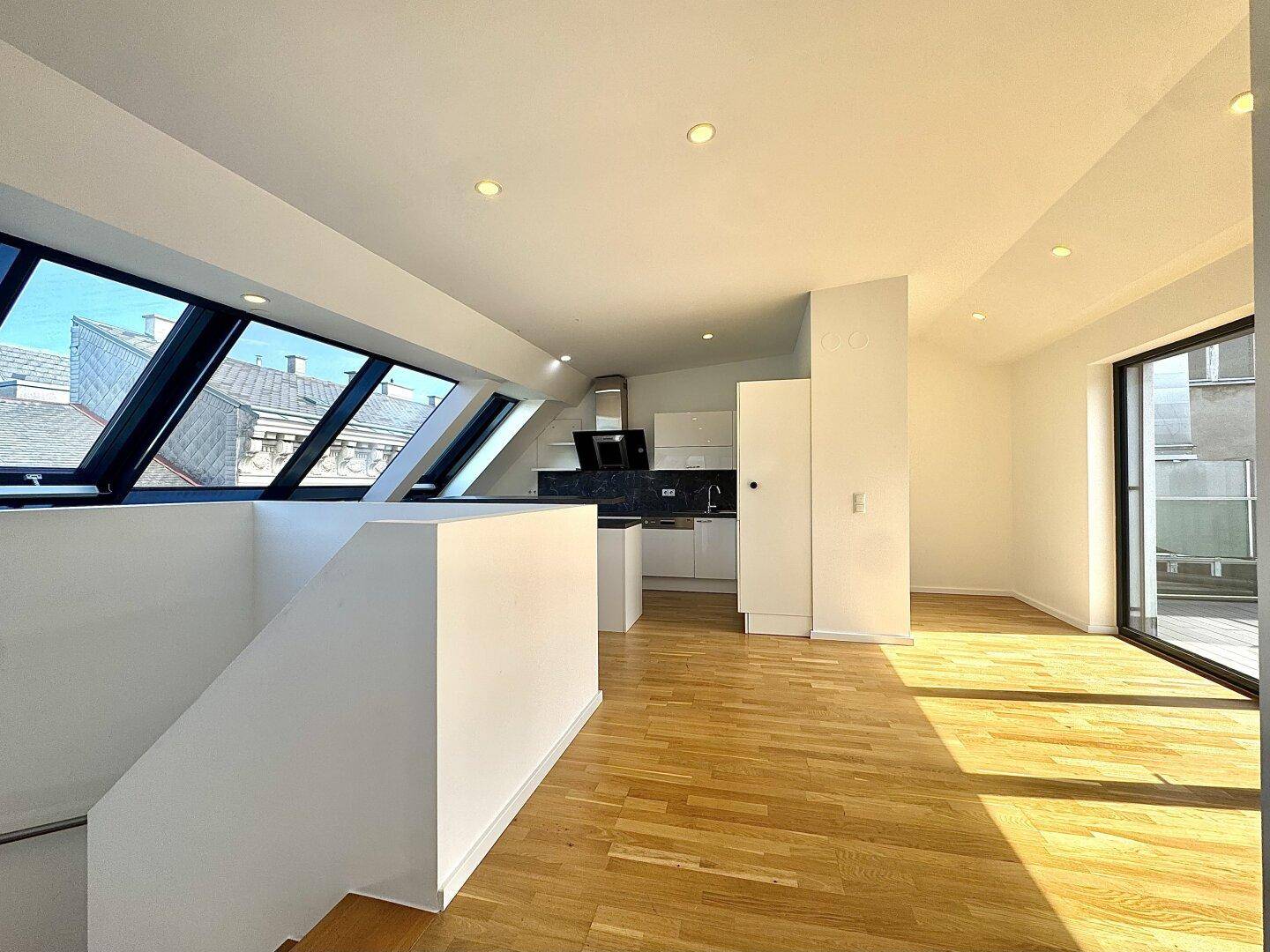 Lichtdurchfluteter Wohnbereich mit offener Küche, Parkettboden und Zugang zur Terrasse.