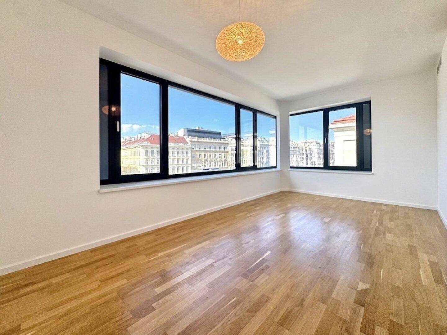 Helles Schlafzimmer mit Parkettboden und weitem Stadtblick durch große Fenster.