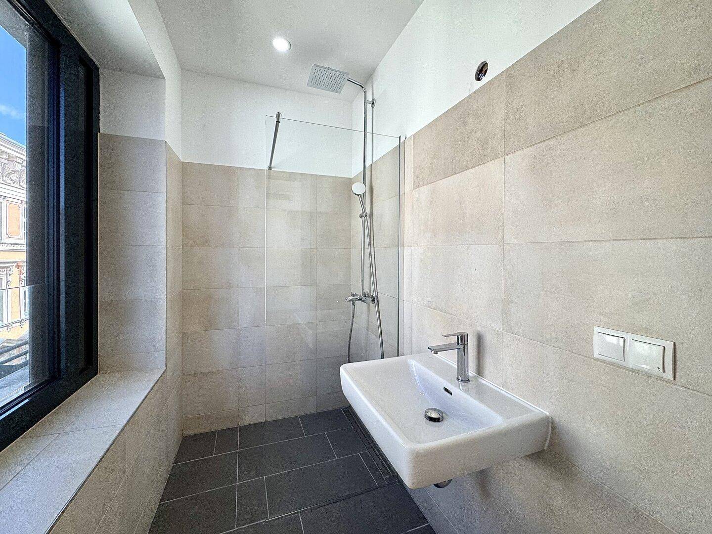 Zeitgemäßes Badezimmer mit ebenerdiger Dusche, Einzelwaschbecken und Fenster.