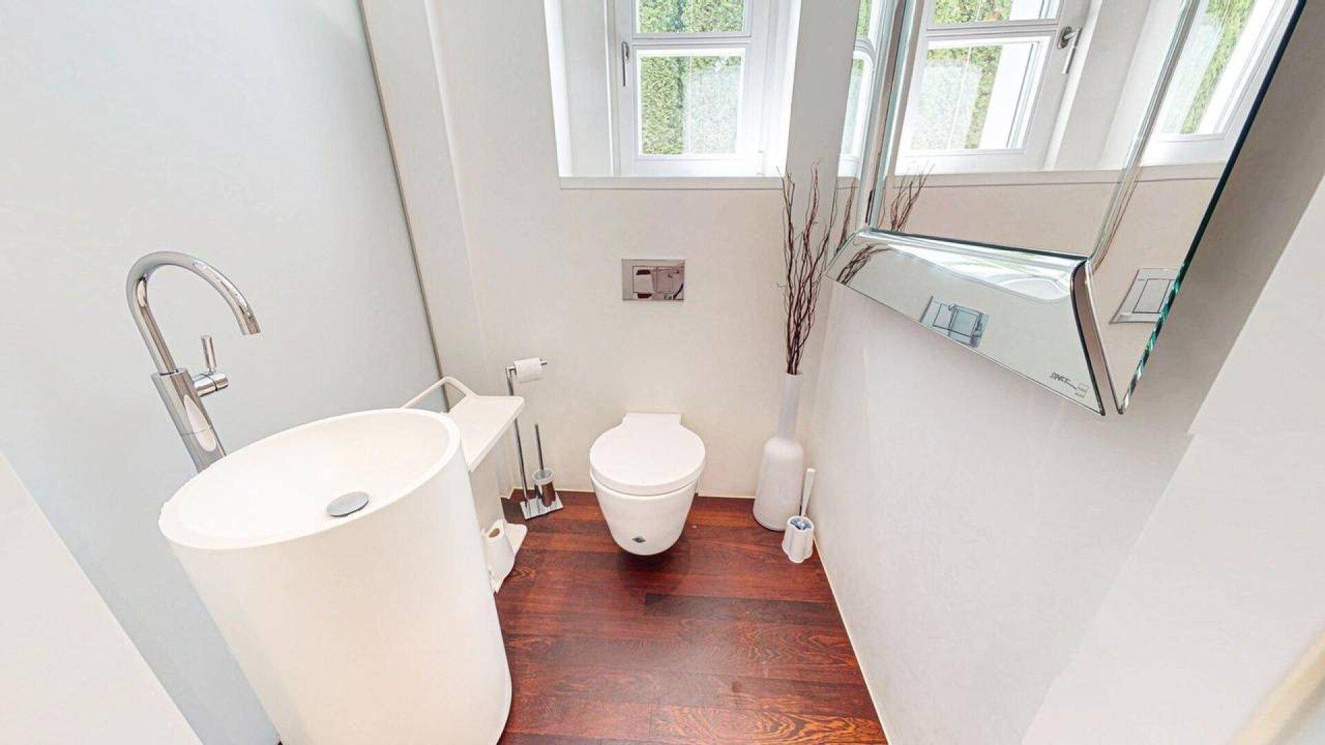 Modernes Gäste-WC mit freistehendem Waschbecken, Wand-WC und Holzboden.
