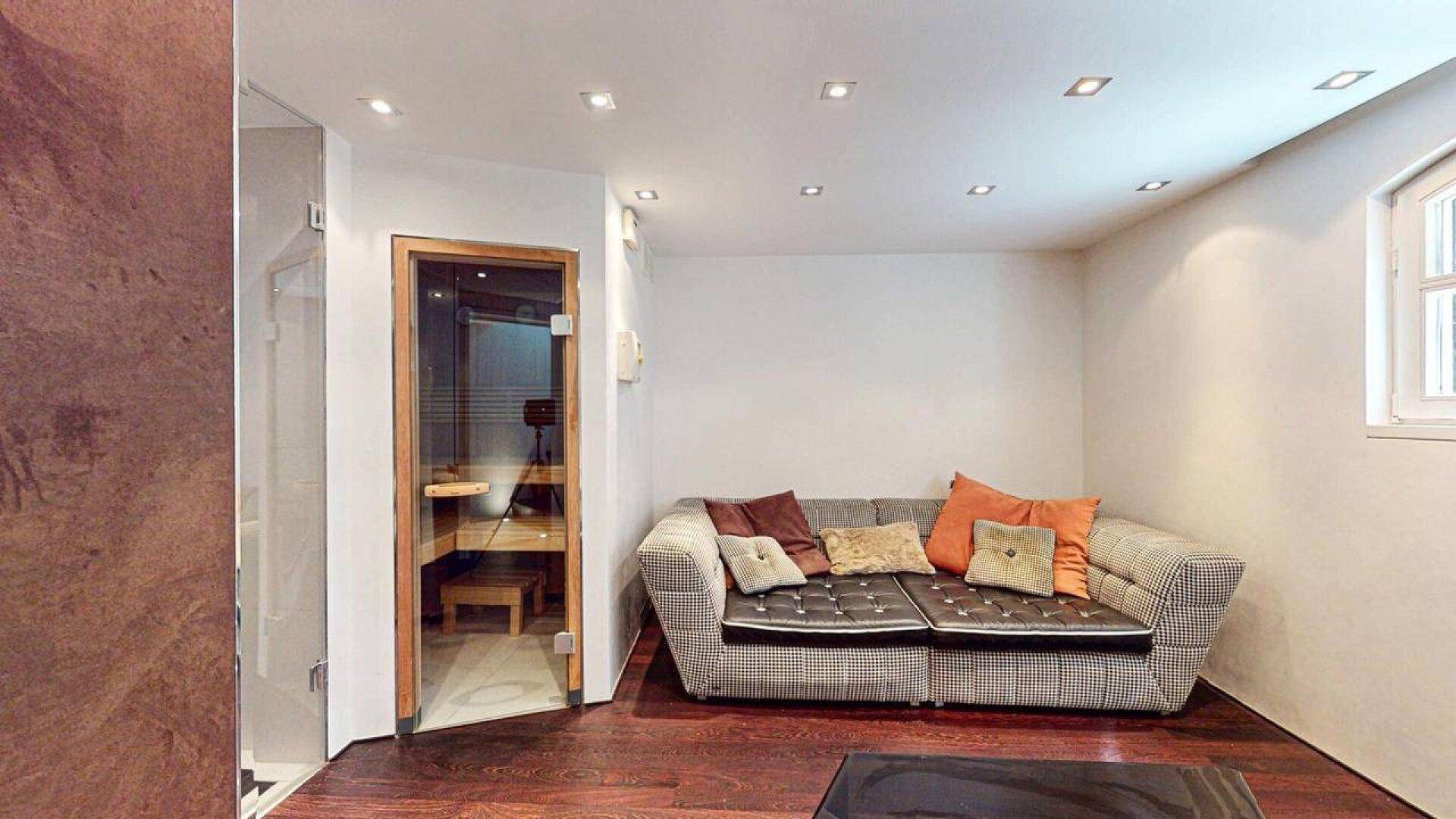 Gemütlicher Bereich im Untergeschoss mit Sauna und Sofa für Entspannung.
