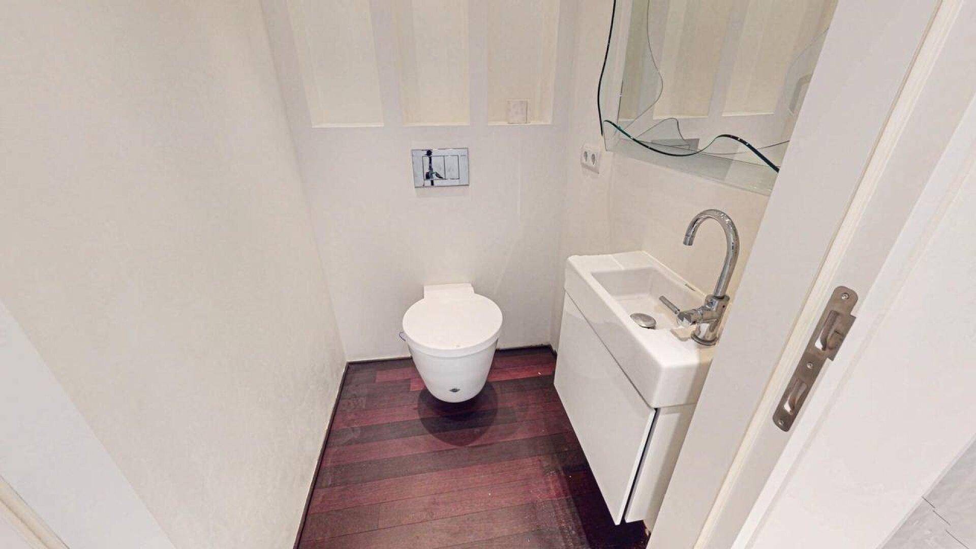 Kleines Gäste-WC mit modernem Waschbecken, Wand-WC und Holzboden.