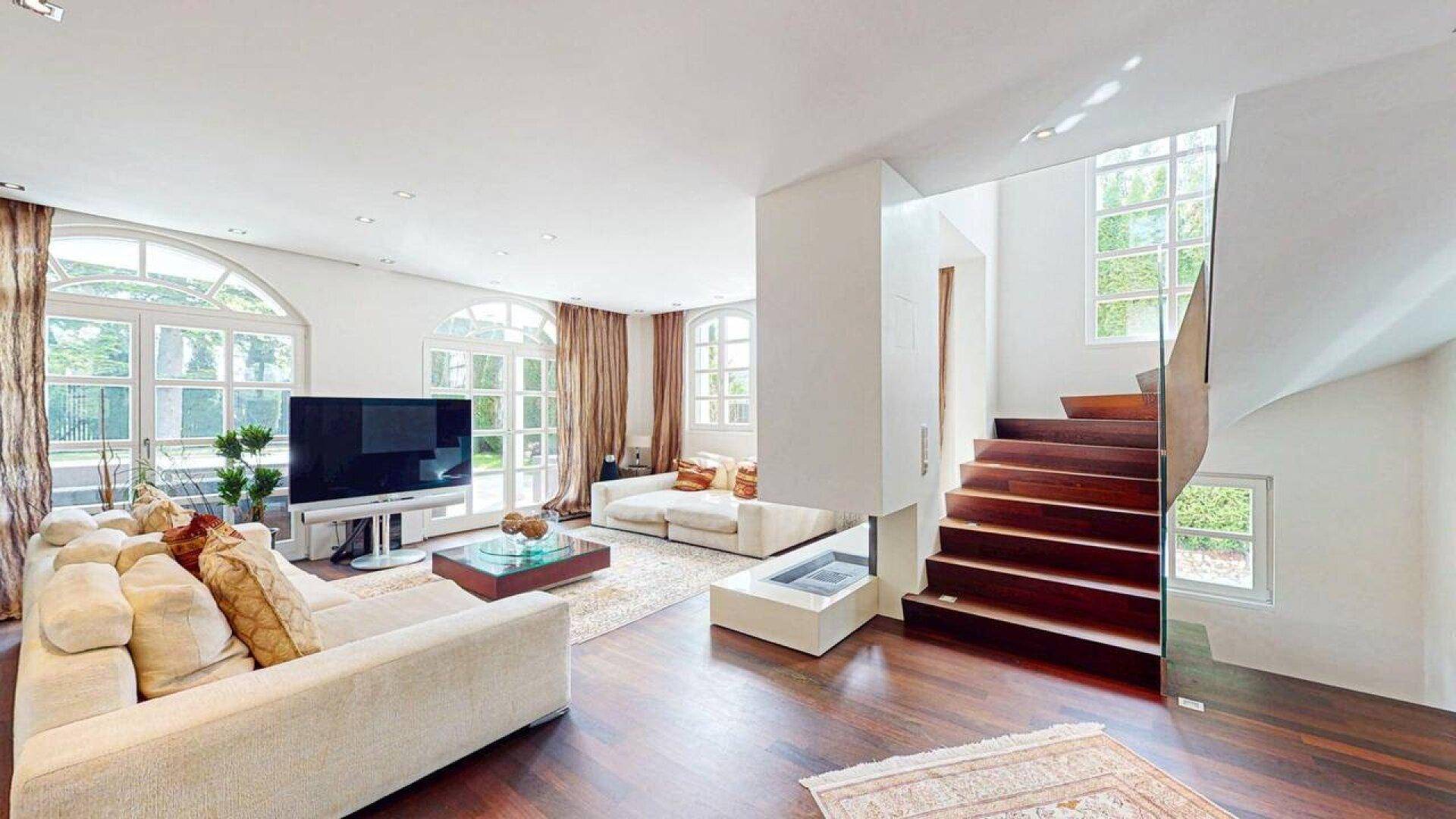 Helles Wohnzimmer mit Holzboden, modernem Kamin und eleganter Treppe.