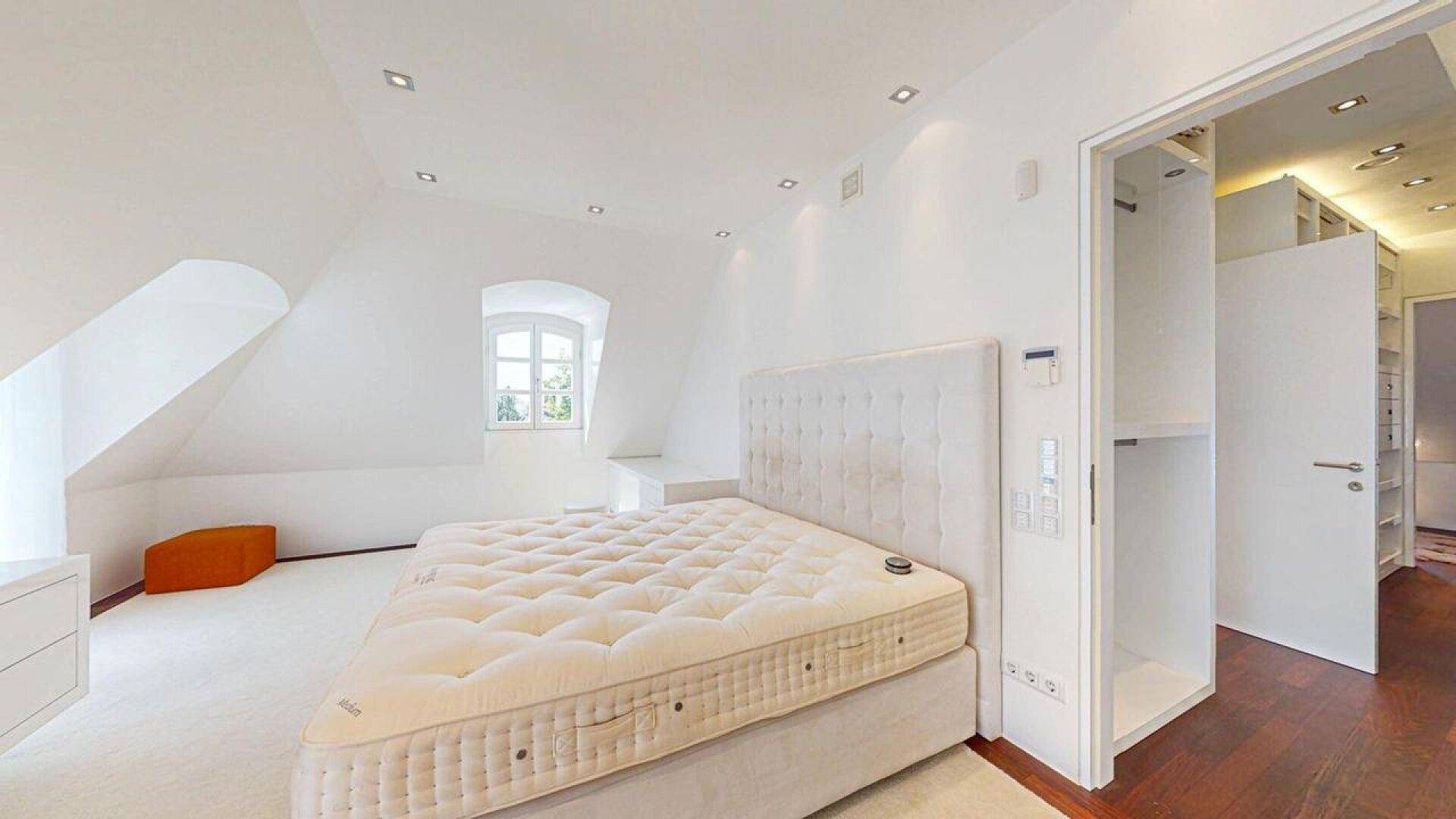 Helles Schlafzimmer im Dachgeschoss mit Zugang zum begehbaren Kleiderschrank.