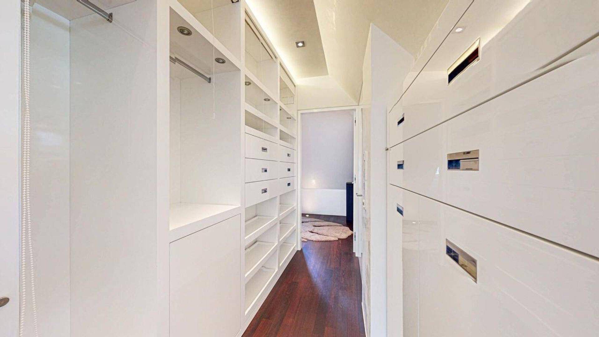 Geräumiger begehbarer Kleiderschrank mit vielen Regalen und Schubladen.