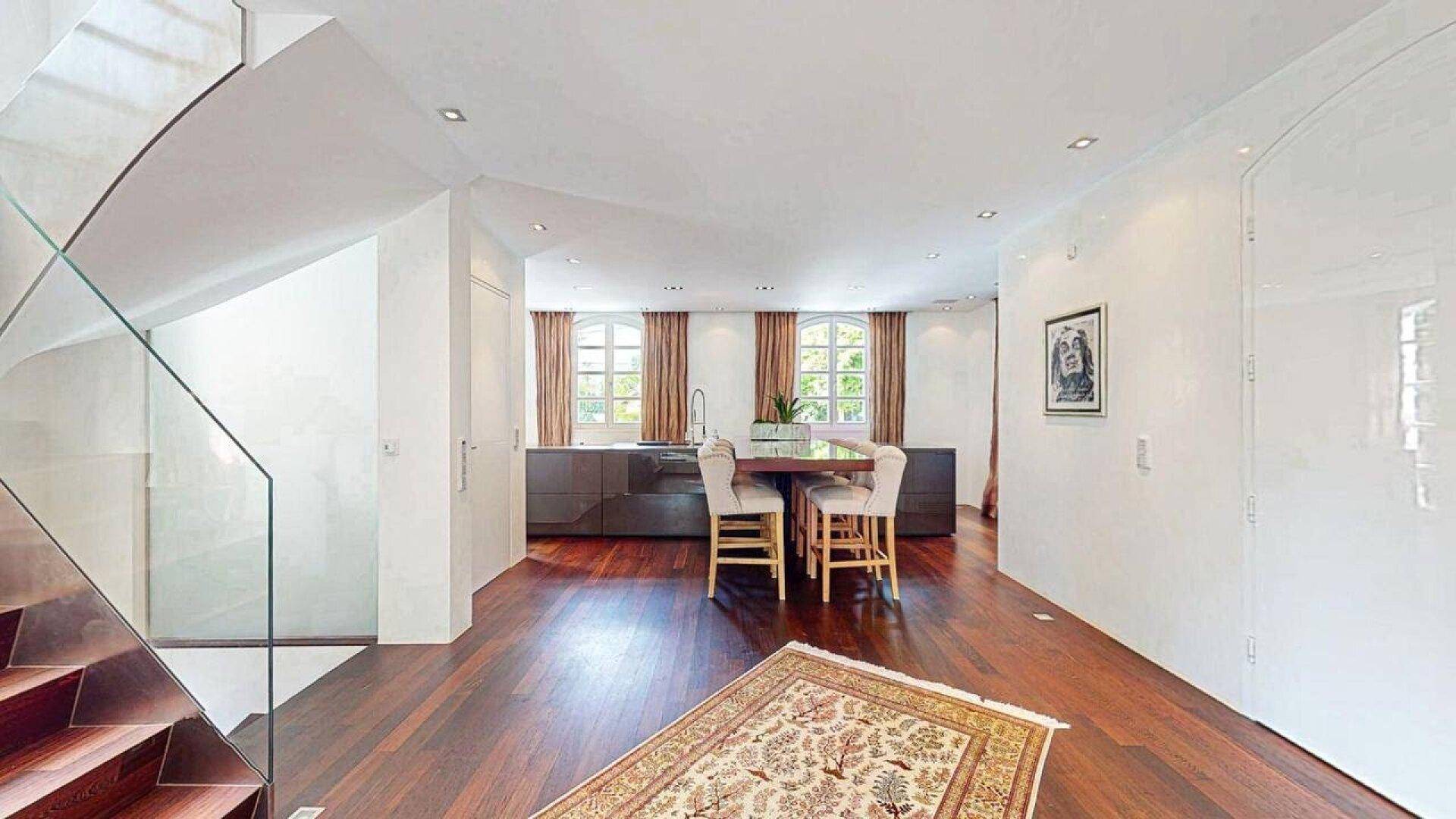 Offene Küche mit Essbereich und Blick auf die moderne Treppe im Hintergrund.