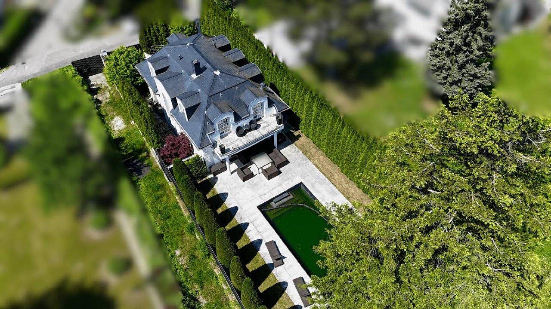 Luftaufnahme des Anwesens mit Villa, Pool und umgebender grüner Hecke.
