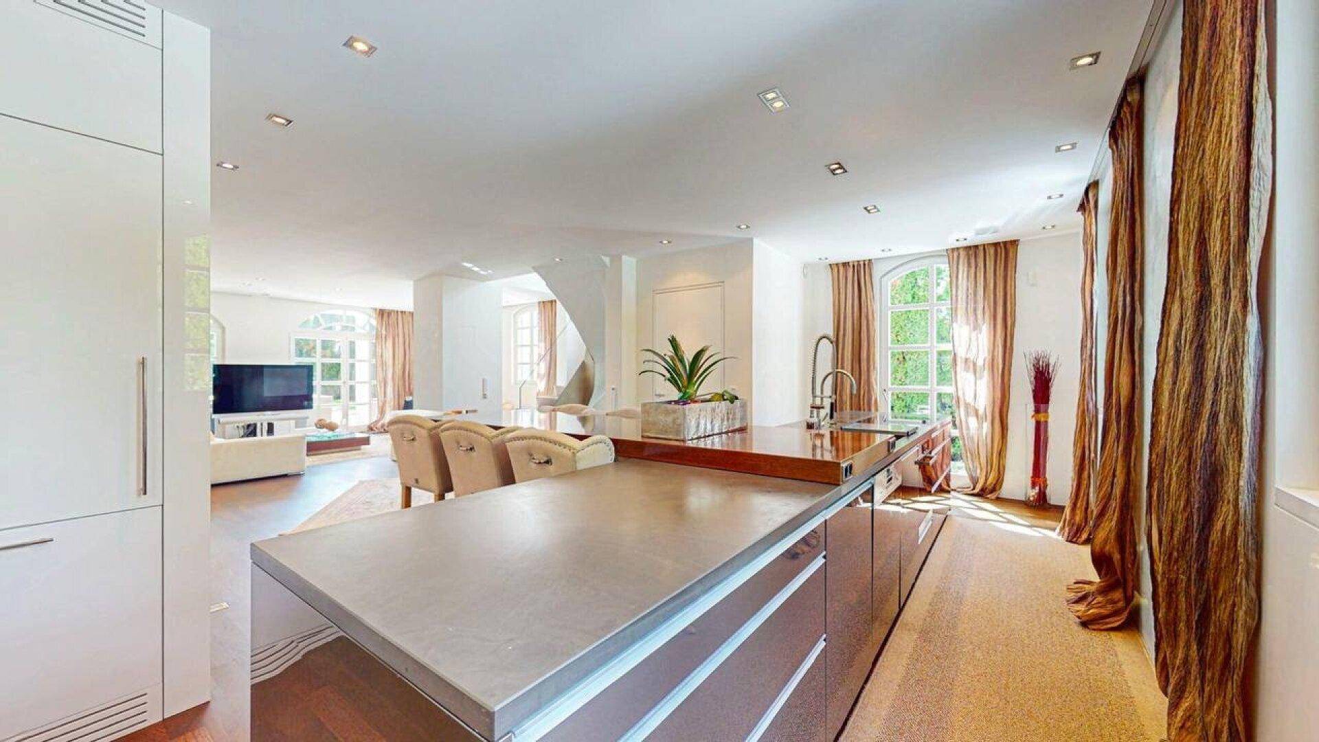 Geräumige Küche mit moderner Kücheninsel und offenem Blick auf den Wohnbereich und die Treppe.