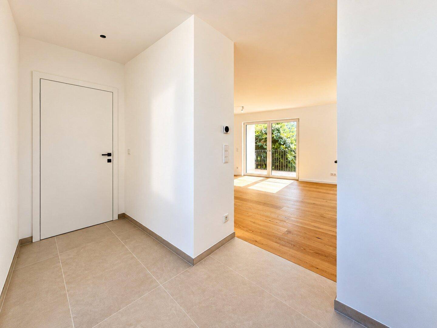 Heller Eingangsbereich mit Fliesenboden, der in den offenen Wohnbereich des Hauses führt.