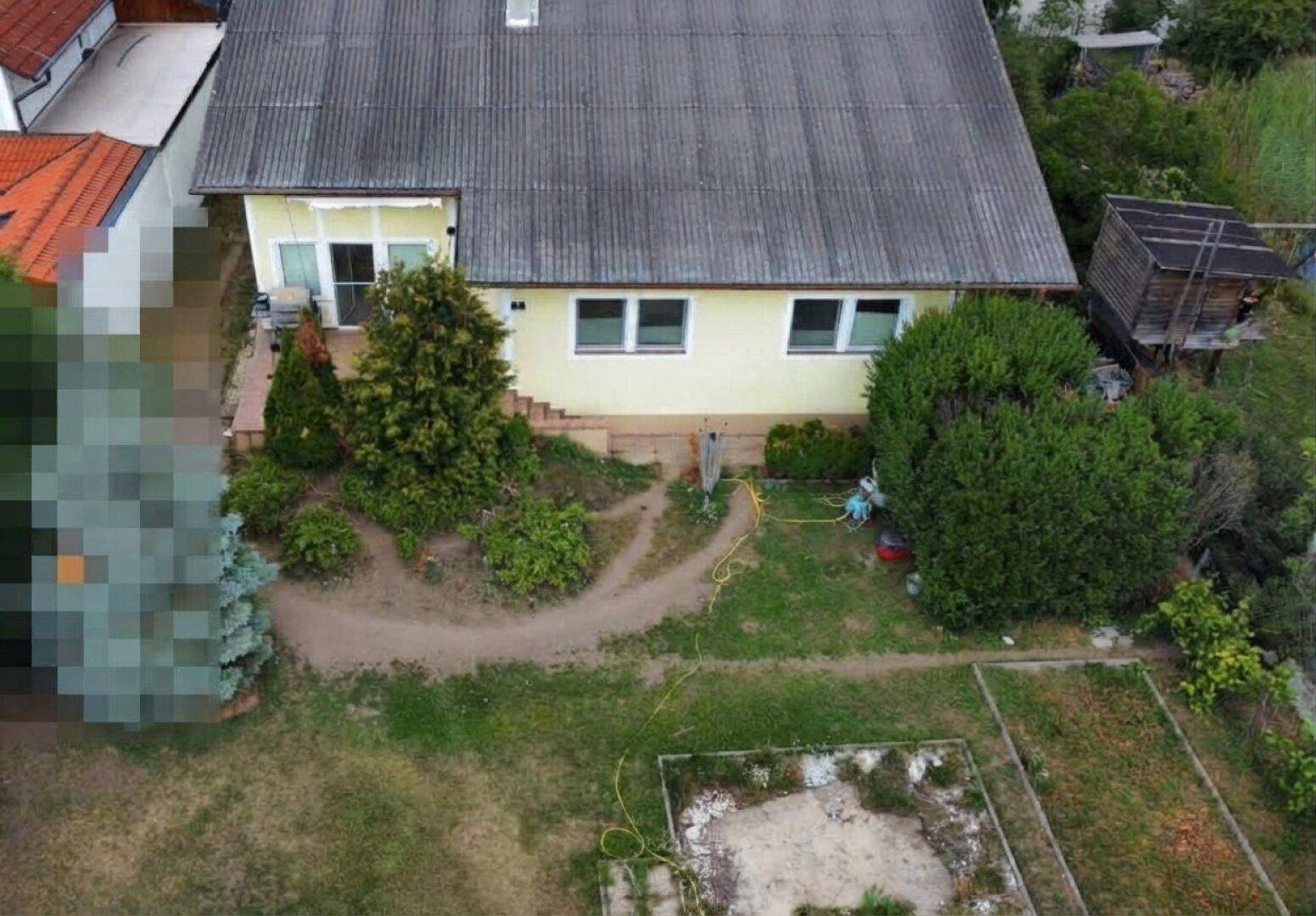Luftaufnahme des Hauses mit großem Garten, Rasenfläche und kleiner Terrasse im hinteren Bereich.