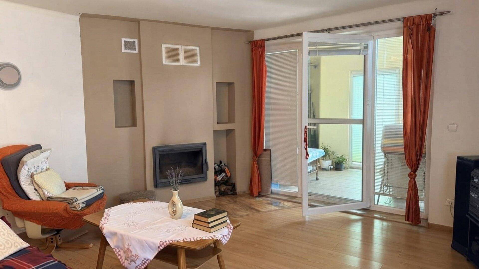 Gemütliches Wohnzimmer mit Kamin, Holzboden und direktem Zugang zu einer sonnigen Terrasse.