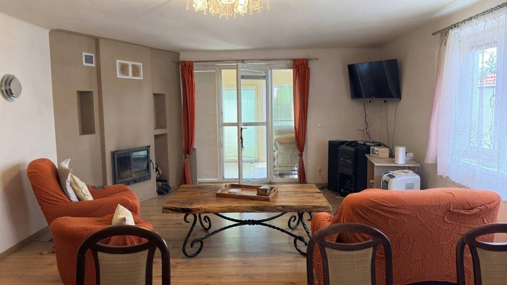 Gemütliches Wohnzimmer mit Kamin, Holzboden und Zugang zu einem hellen Außenbereich.