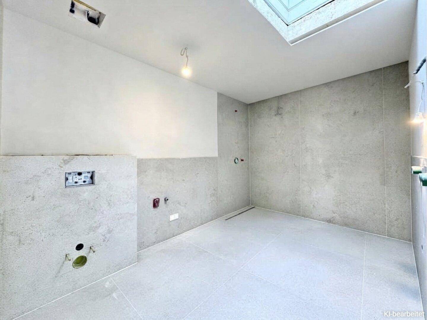 Unfertiges Badezimmer mit modernen grauen Fliesen, Oberlicht und Vorbereitung für eine begehbare Dusche.
