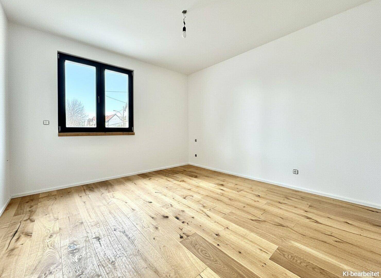 Helles Schlafzimmer mit Holzboden und einem Fenster, bereit zur individuellen Gestaltung.
