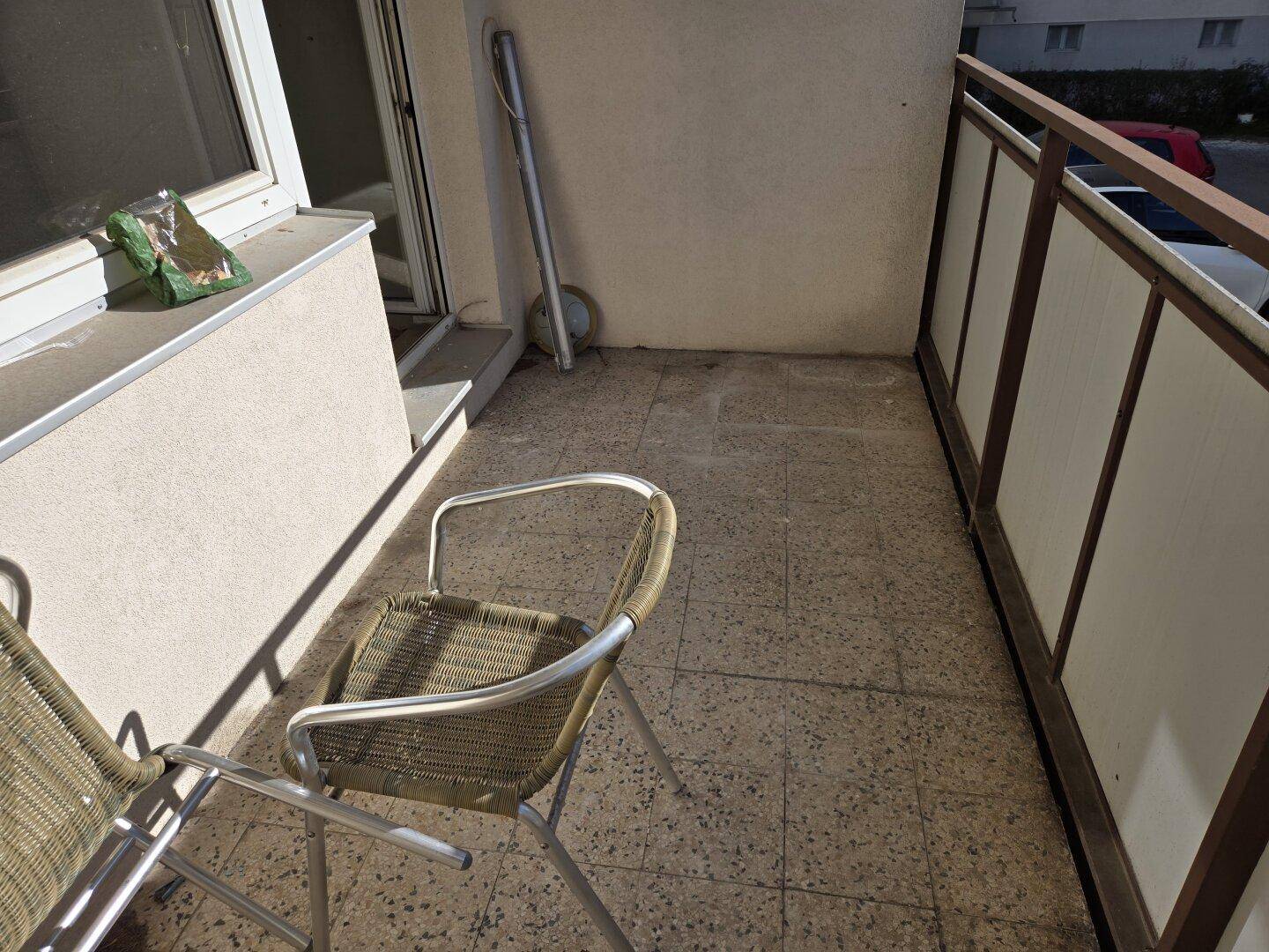 Kleiner Balkon mit Fliesenboden und zwei Stühlen, ideal für eine Kaffeepause im Freien.