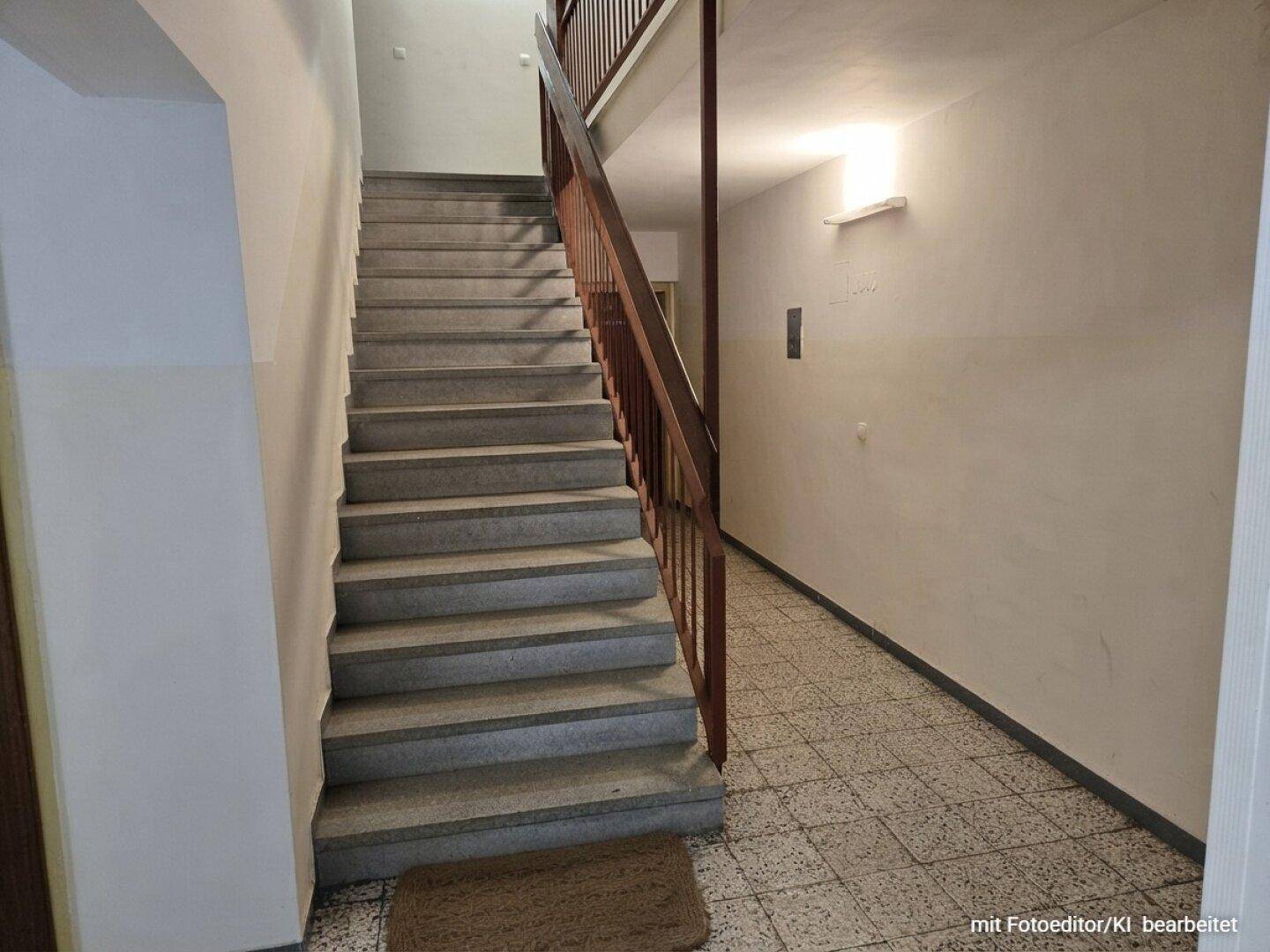 Treppenhaus mit Steinstufen und Holzgeländer, führt zu den oberen Etagen des Gebäudes.