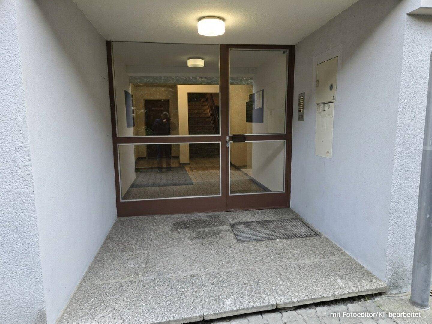 Haupteingang des Gebäudes mit großer Glastür, Gegensprechanlage und barrierefreier Rampe.