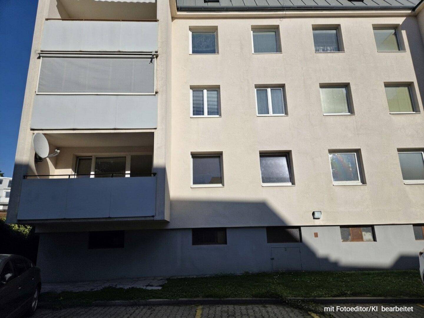 Fassade eines Mehrfamilienhauses mit mehreren Balkonen und Fenstern unter blauem Himmel.