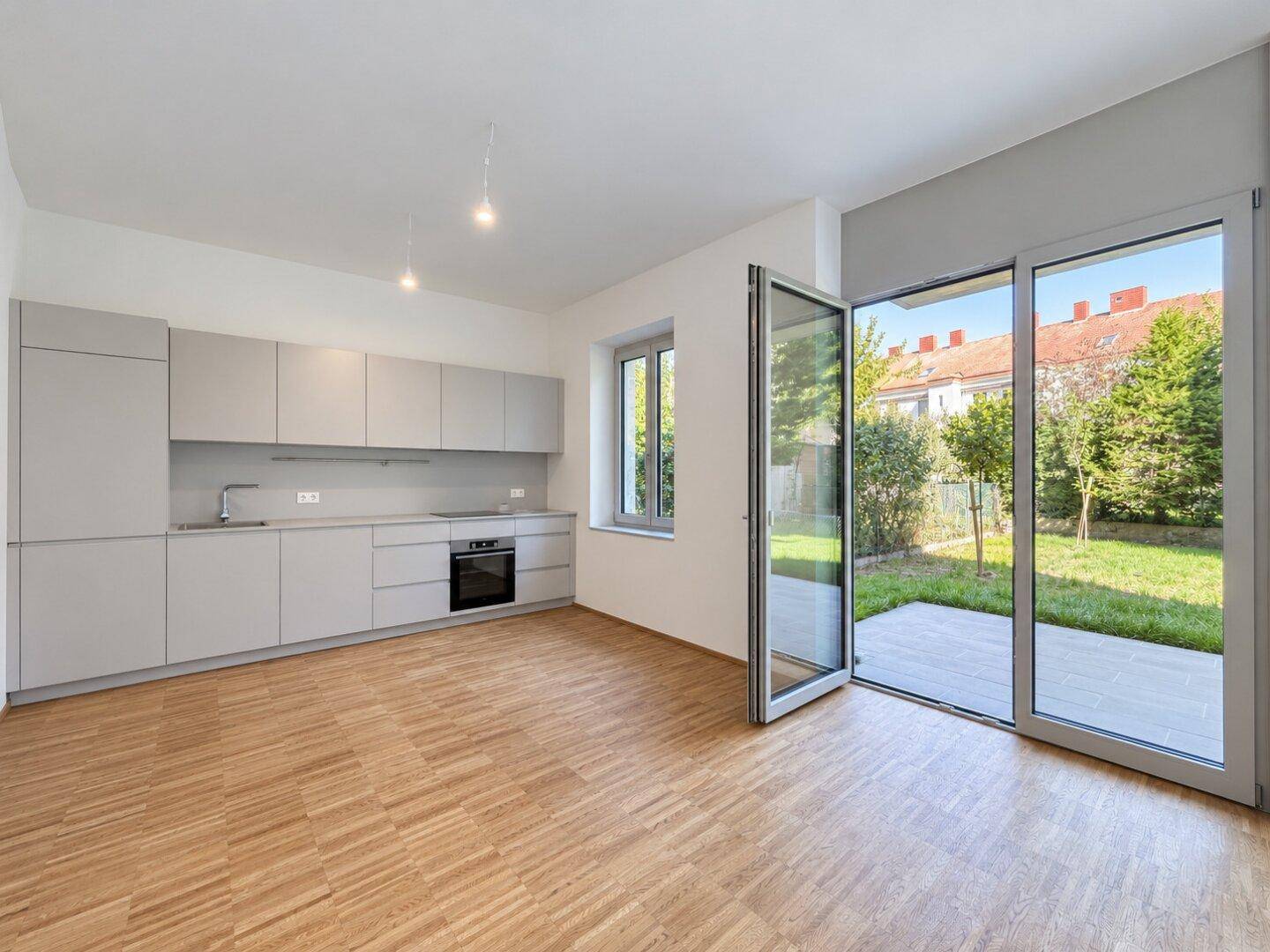 Moderne Einbauküche in Grau mit integrierten Geräten und direktem Zugang zur Terrasse und zum Garten.