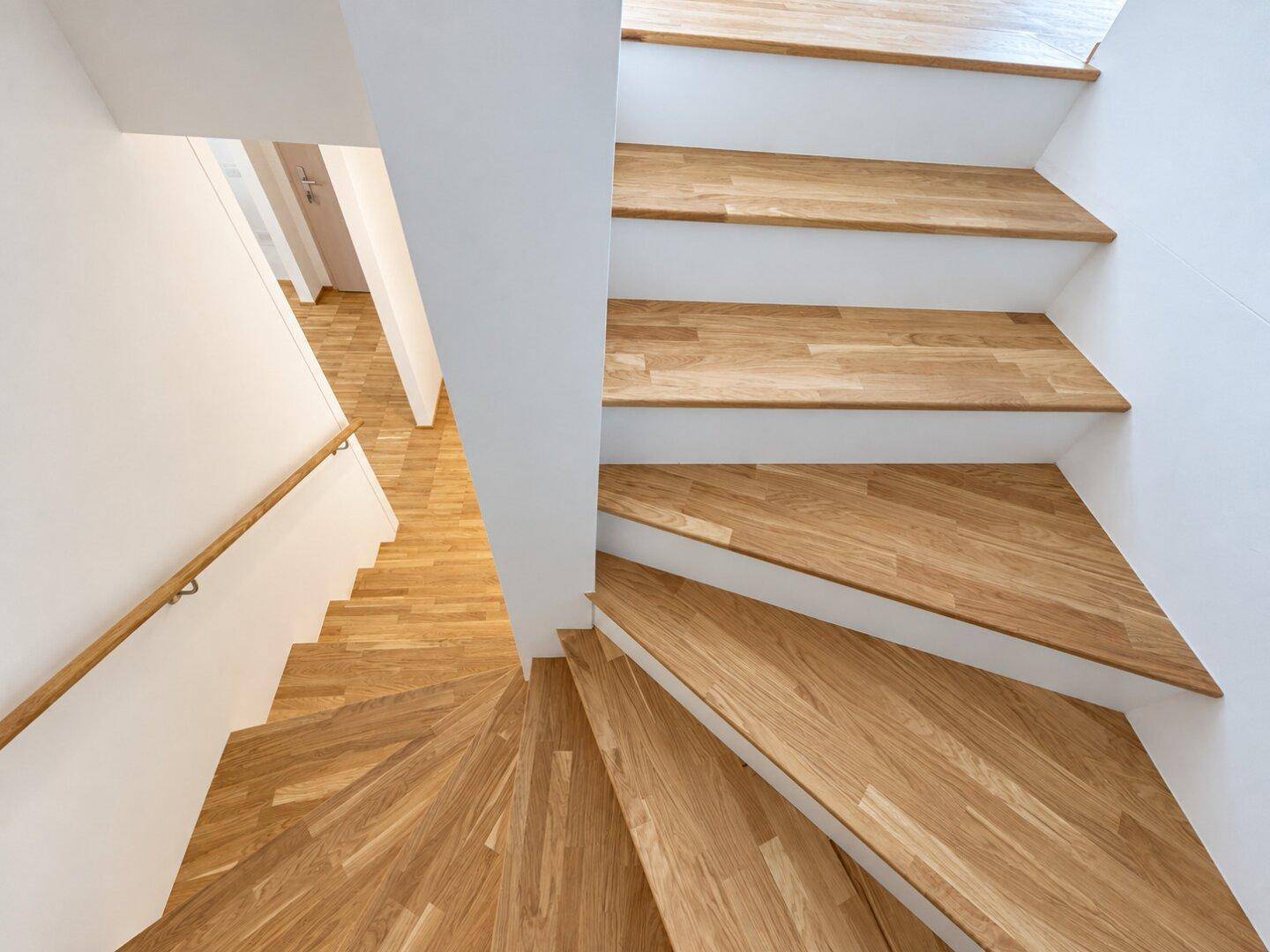 Moderne Holztreppe mit hellem Geländer, die die verschiedenen Etagen des Hauses verbindet.