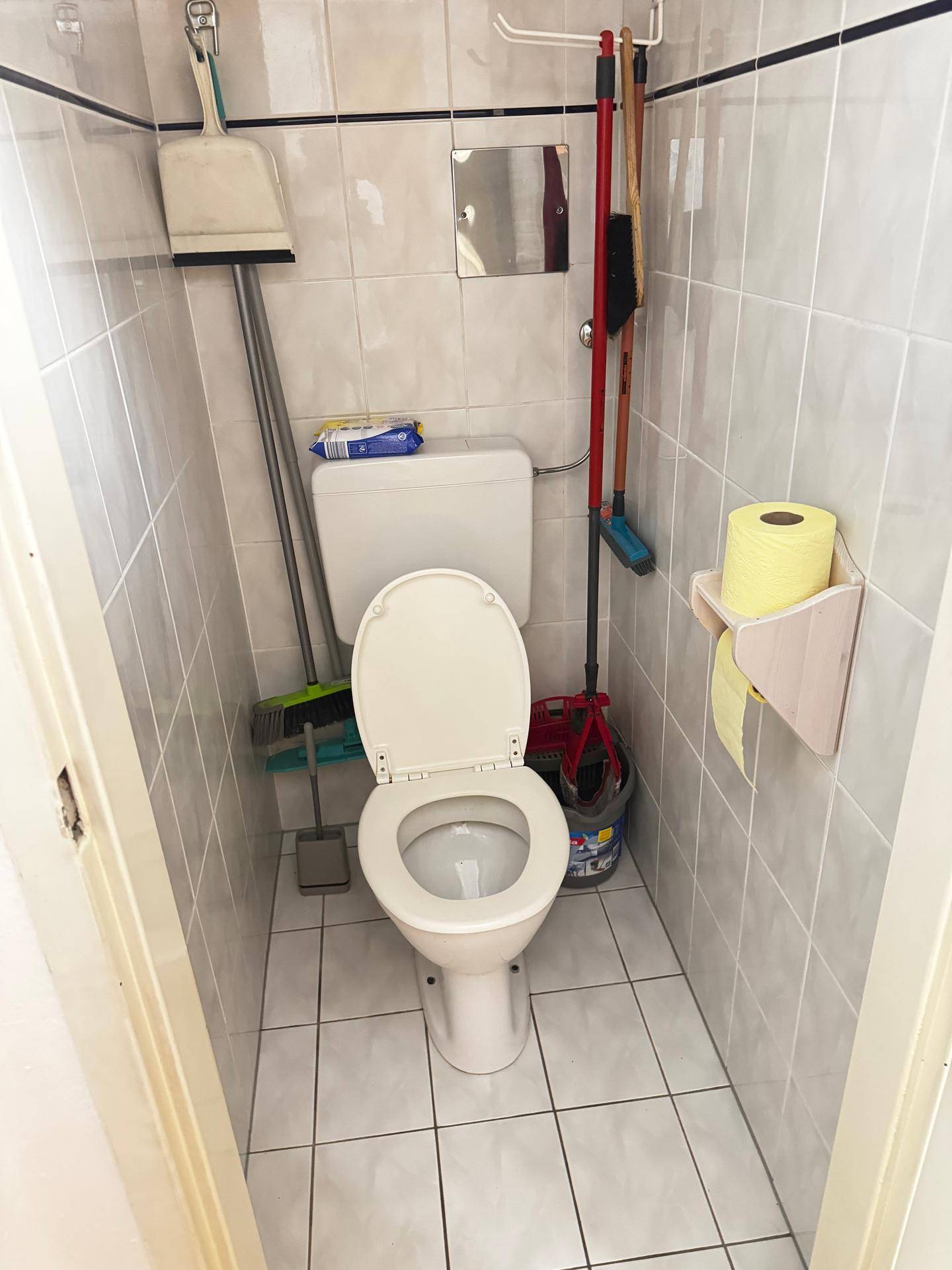 Kleines separates WC mit Toilette und hellen Fliesen an Wänden und Boden.