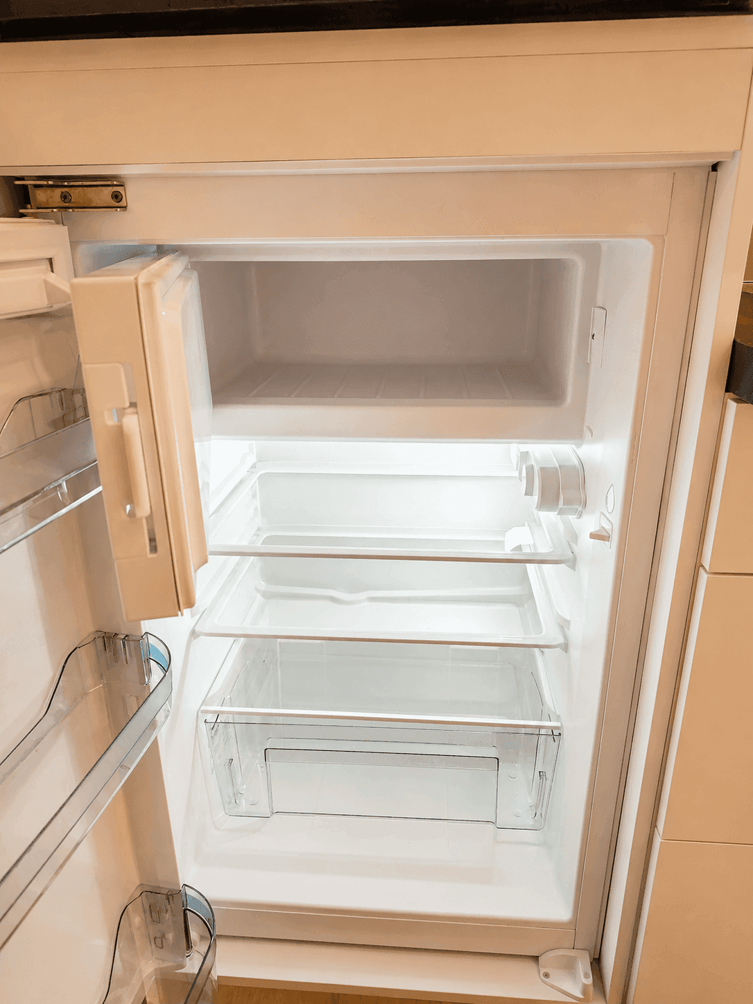 Offener Kühlschrank mit leeren Fächern, bereit zur Befüllung.