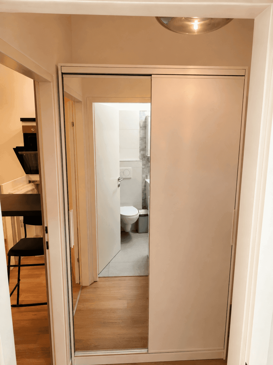 Flur mit Spiegelschiebetürenschrank und Blick in das angrenzende Badezimmer.