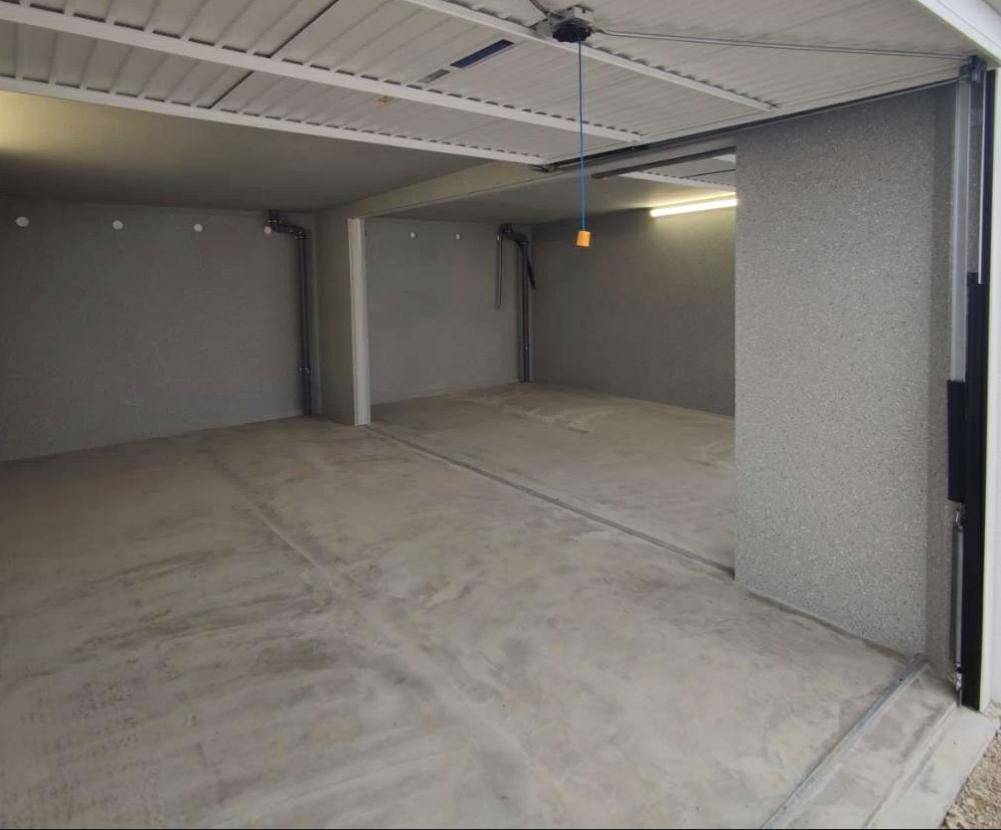 Leere Garage mit Betonboden und strukturierten Wänden, bereit zur Nutzung.