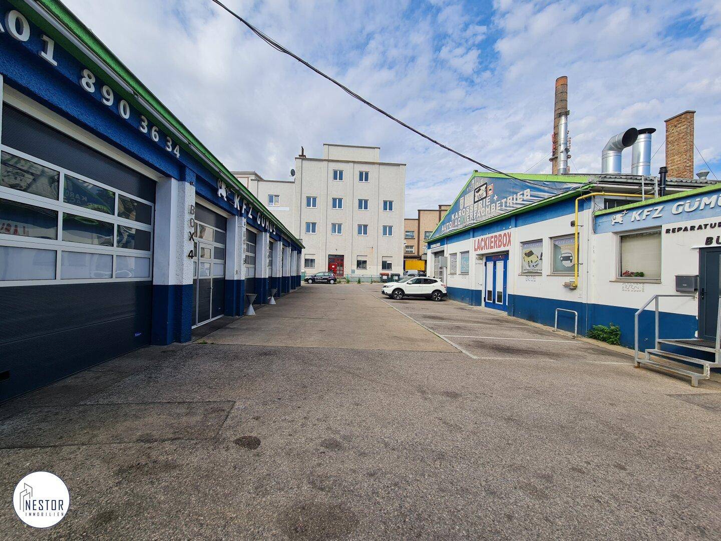 Blick auf die Reihe der Garagentore des Gewerbegebäudes und den angrenzenden Bau unter blauem Himmel.