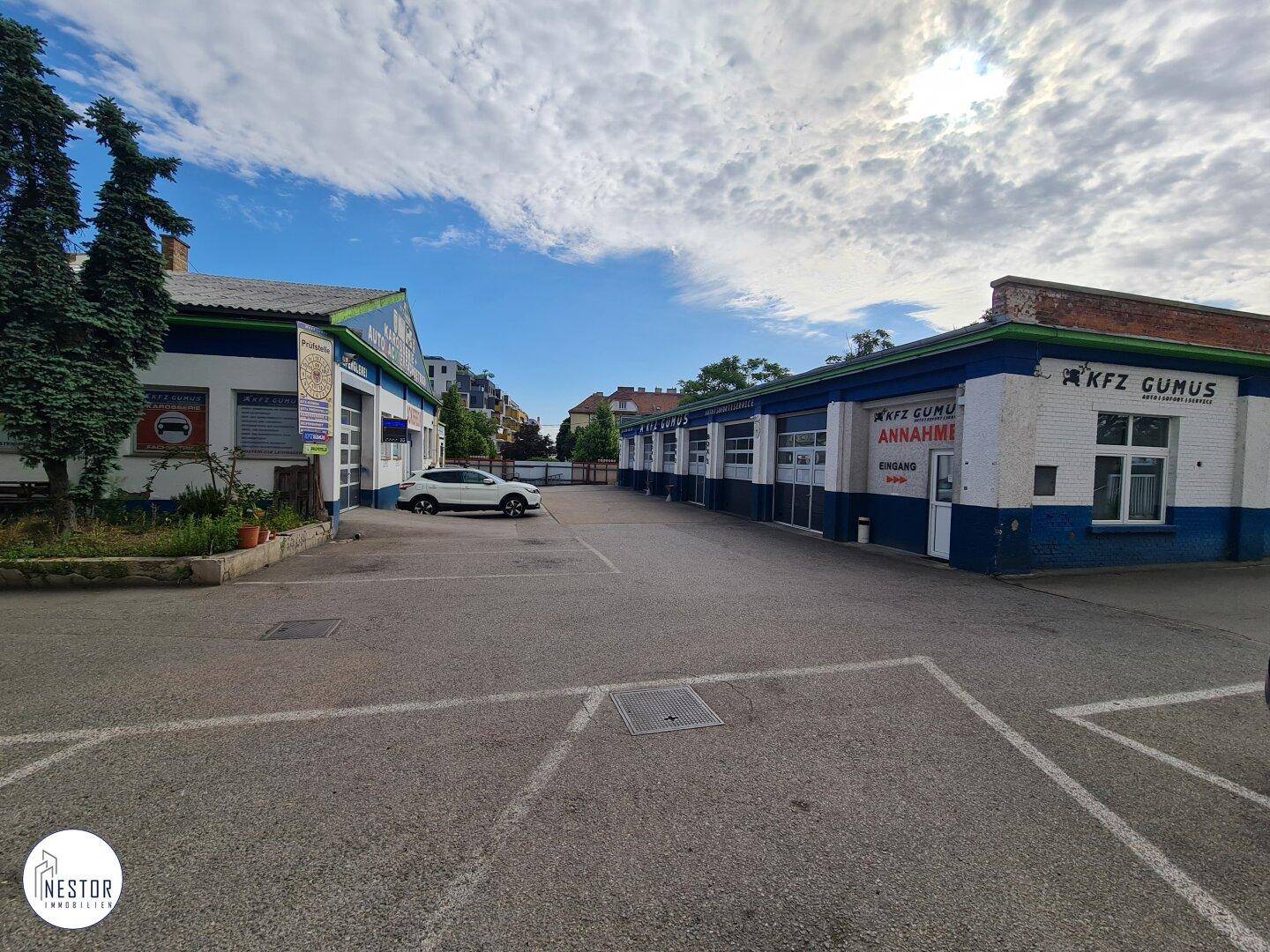 Außenansicht aus einem anderen Winkel, die beide Hauptbereiche des Gebäudes und den weitläufigen Parkplatz zeigt.