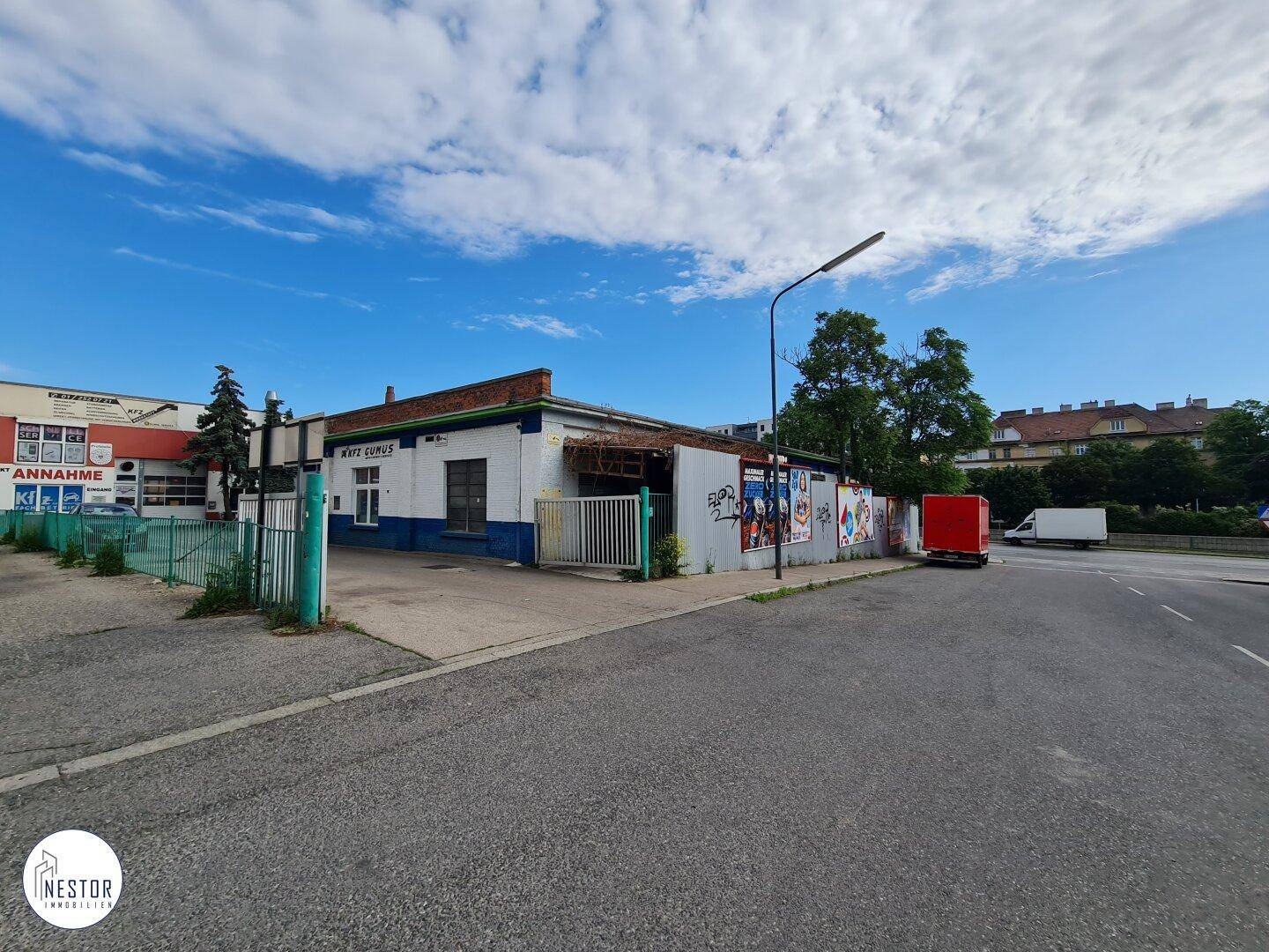 Außenansicht von der Straße, die die Seite des Gewerbegebäudes mit Graffiti und einem vorbeifahrenden roten LKW zeigt.