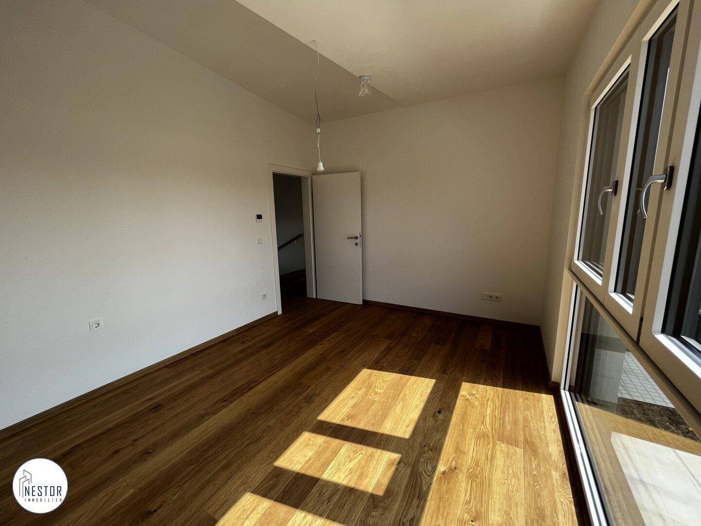 Helles, unmöbliertes Zimmer mit Holzboden und Fenster, ideal als Schlaf- oder Arbeitszimmer.