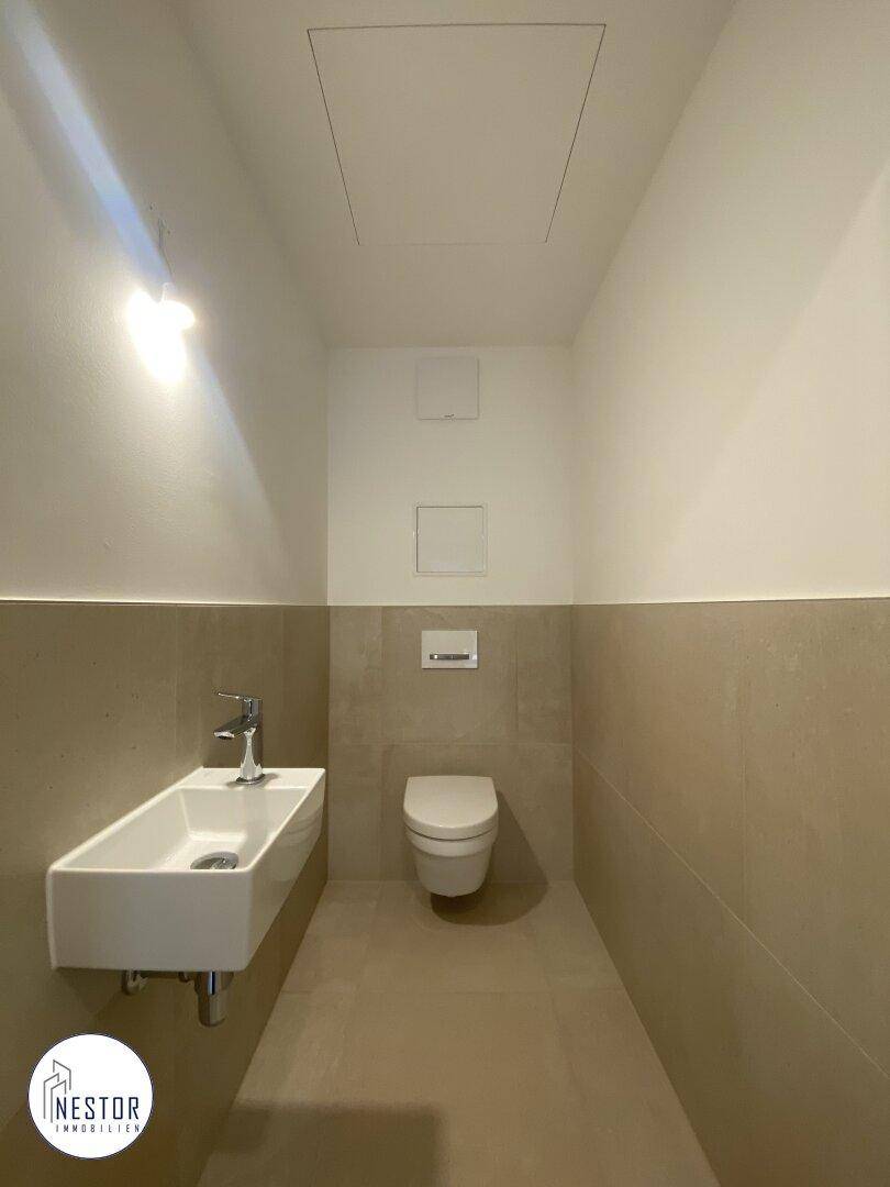 Sauberes Gäste-WC mit wandhängender Toilette und modernem Waschbecken.