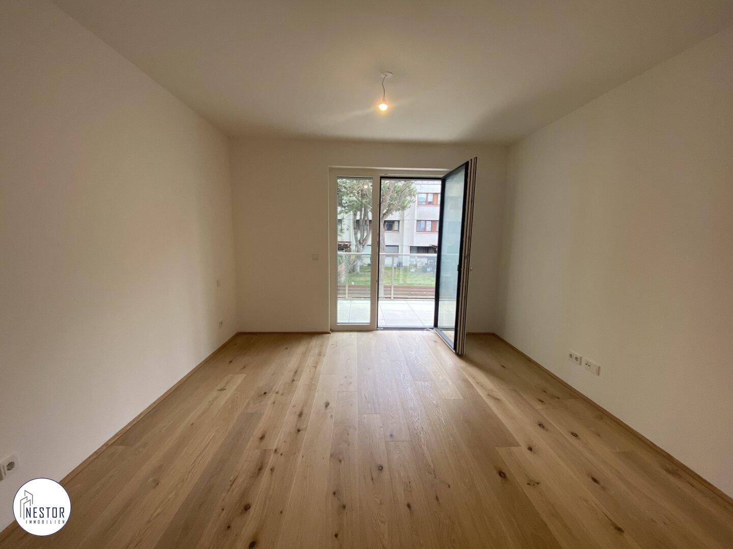 Lichtdurchfluteter Wohnraum mit Holzboden und großer Schiebetür zum Außenbereich.
