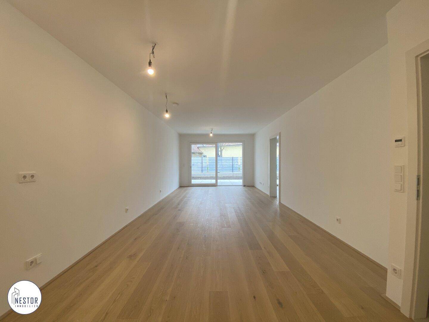 Helles Wohnzimmer mit Holzboden und Zugang zu einem Außenbereich durch große Schiebetüren.