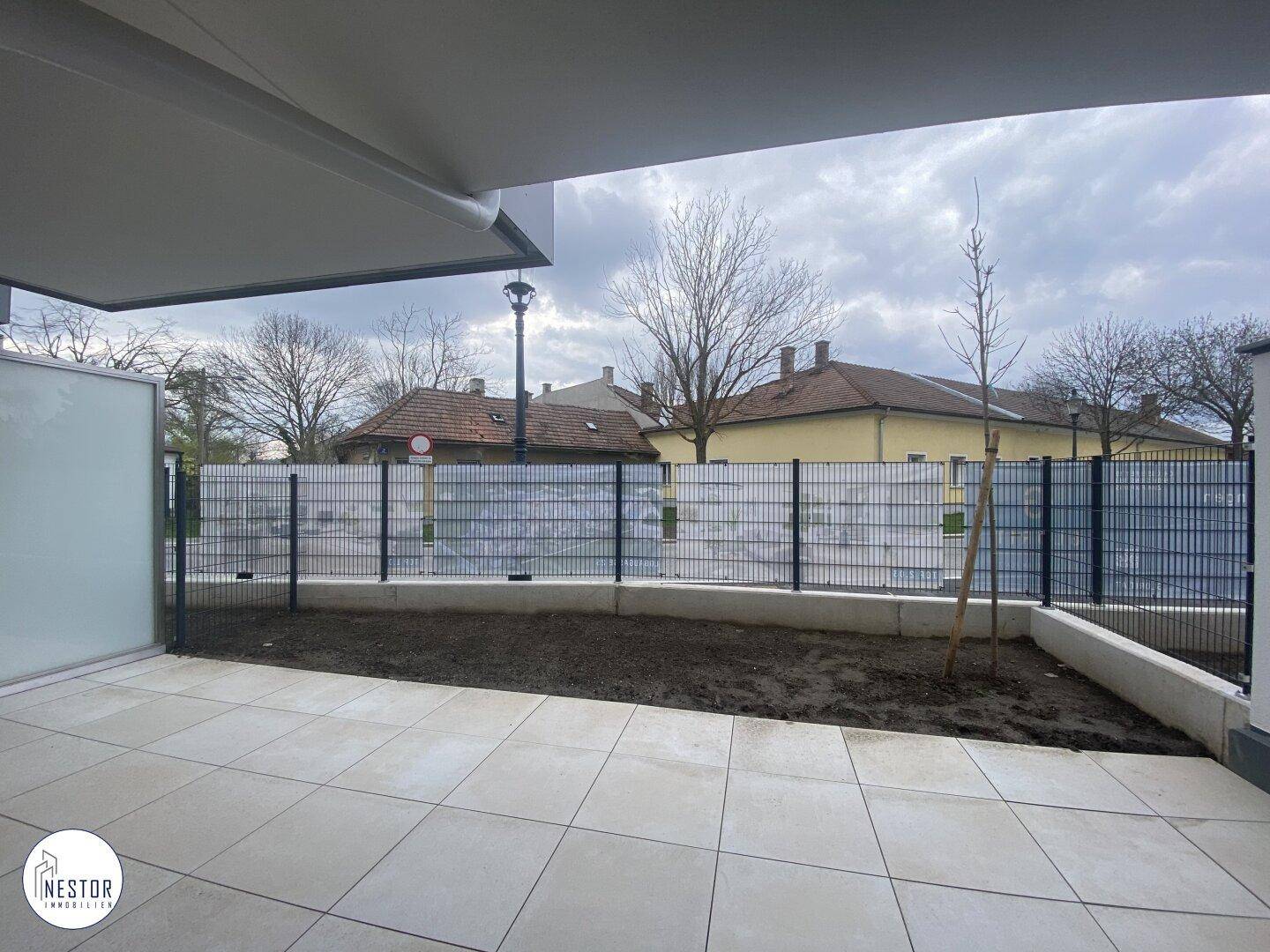 Große, geflieste Terrasse mit angrenzendem Gartenbereich, ideal für Entspannung im Freien.