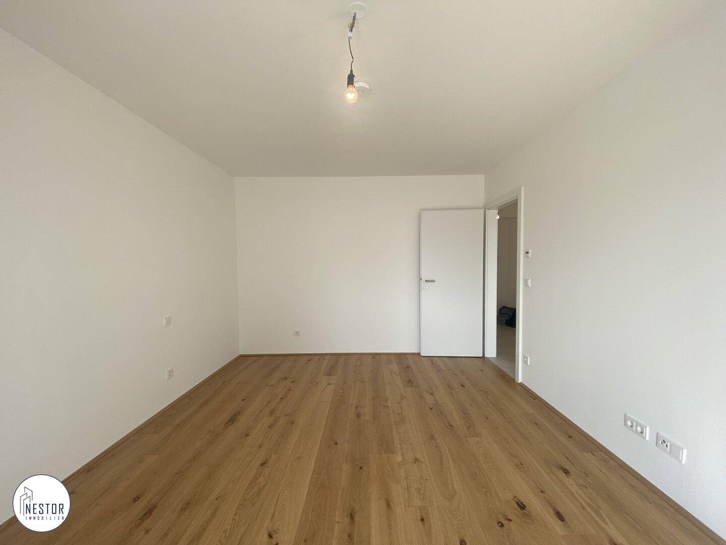 Heller, leerer Raum mit Holzboden und weiß gestrichenen Wänden, bereit für die Einrichtung.