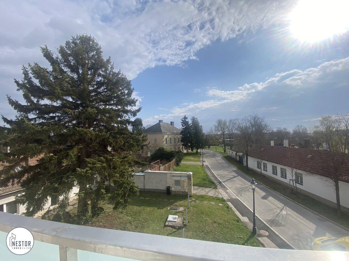 Sonniger Ausblick auf die ländliche Umgebung und eine ruhige Straße mit alten Gebäuden.