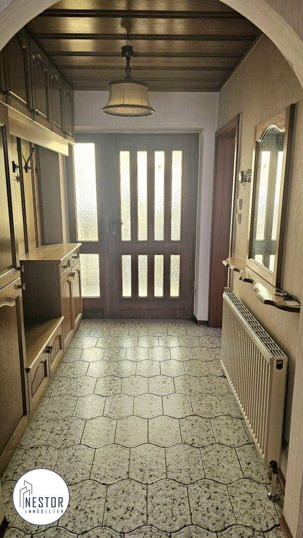 Eingangsbereich mit Fliesenboden, Holzdecke und integrierter Garderobe.