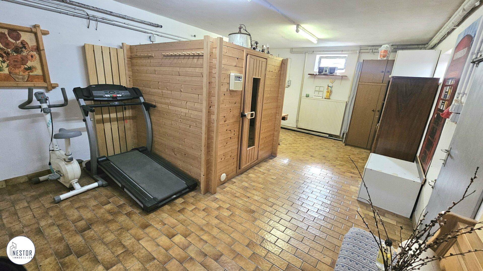 Ausgebauter Kellerraum mit Sauna und Fitnessgeräten, ideal für Wellness und Sport.