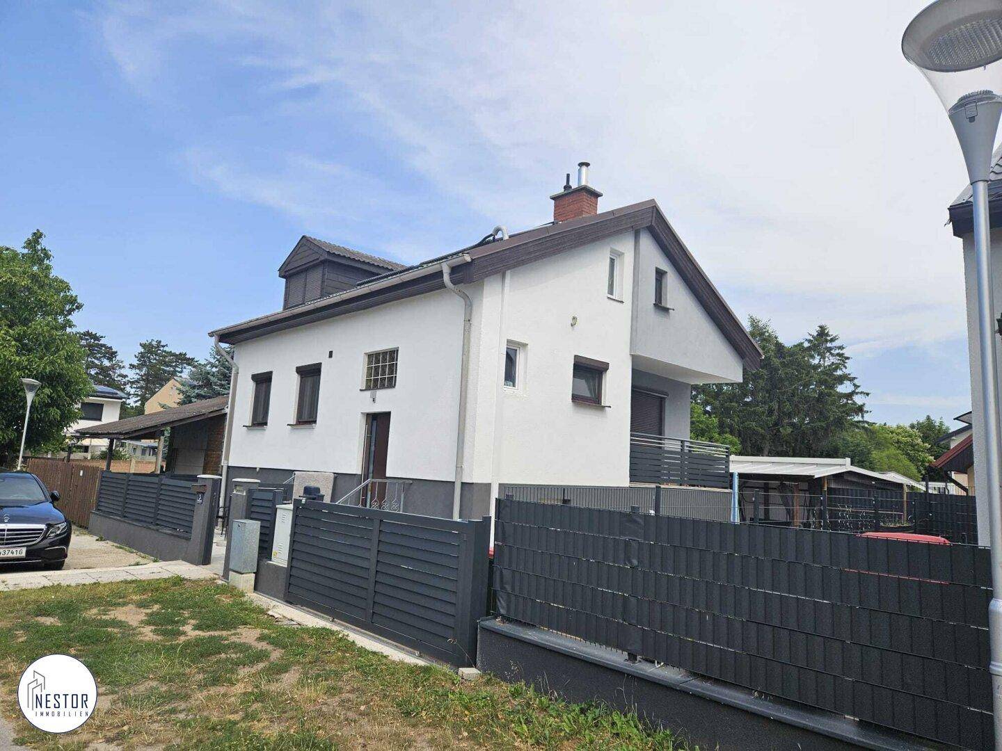 Ansicht des Einfamilienhauses von der Straße mit gepflegtem Vorgarten und Zaun.